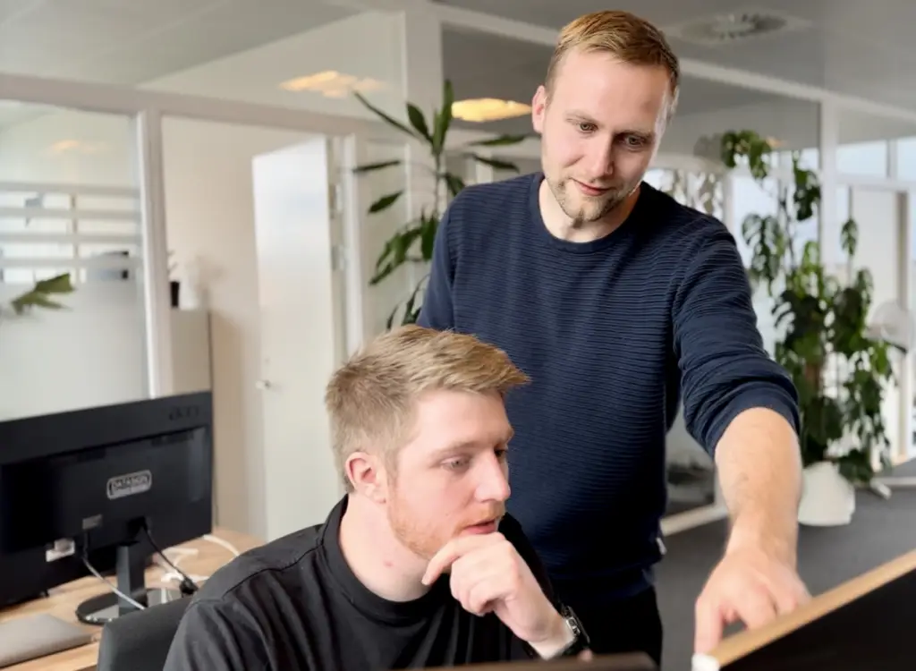 Medarbejdere samarbejder om digital løsning på kontor